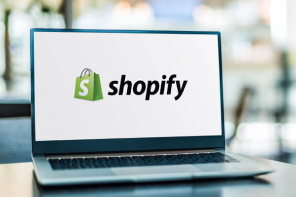 A laptop computer background with the Shopify logo