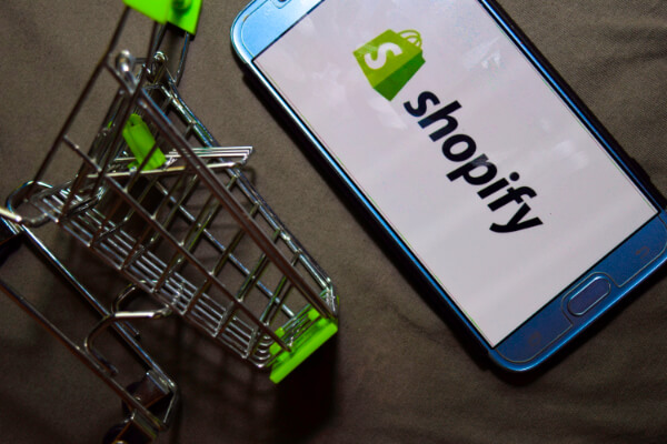 A mobile background with the Shopify logo alongside a cart