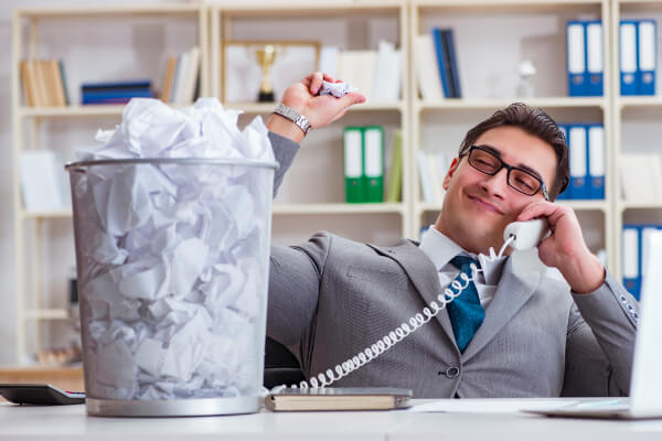 A professional enjoying throwing completed task papers into a bin