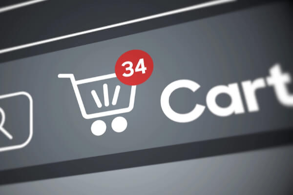 A close-up, high-angle shot of a computer screen showing a bold white "Cart" button and a shopping cart icon with a red circle above it. The red circle displays the number 34, indicating the number of items in the cart.