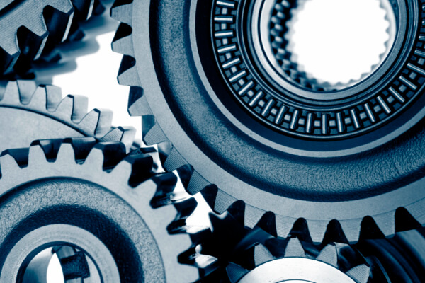 A detailed close-up of multiple interlocking blue-toned metal industrial gears representing mechanical precision.